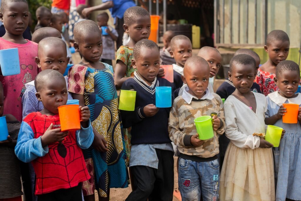 A group of African children holding colorful cups in an outdoor setting.