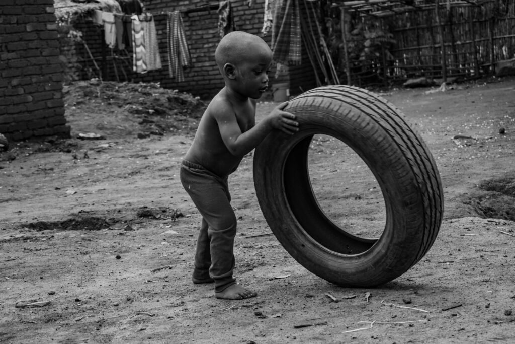 Black and white photo of a young child playing with a tire in Dowa, Malawi.